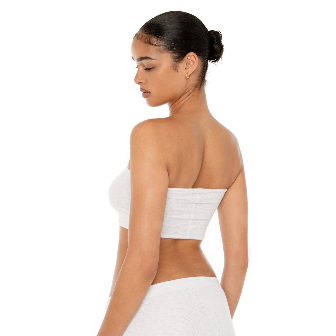 Model wearing the Aili Tube — a minimalist ribbed knit tube top crafted from recycled cotton, offering a snug, barely-there fit that contours to your silhouette**white