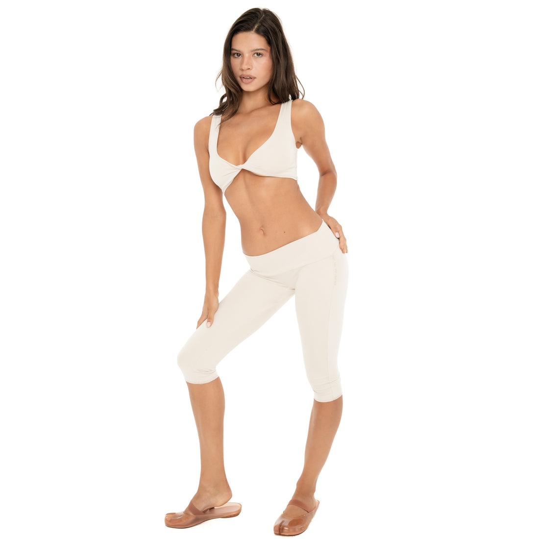 Full look: Model wearing the sand Alue Top with matching capri pants. The cropped ribbed top features a plunging scoop neckline, wide shoulder straps, and twisted front detail **sand