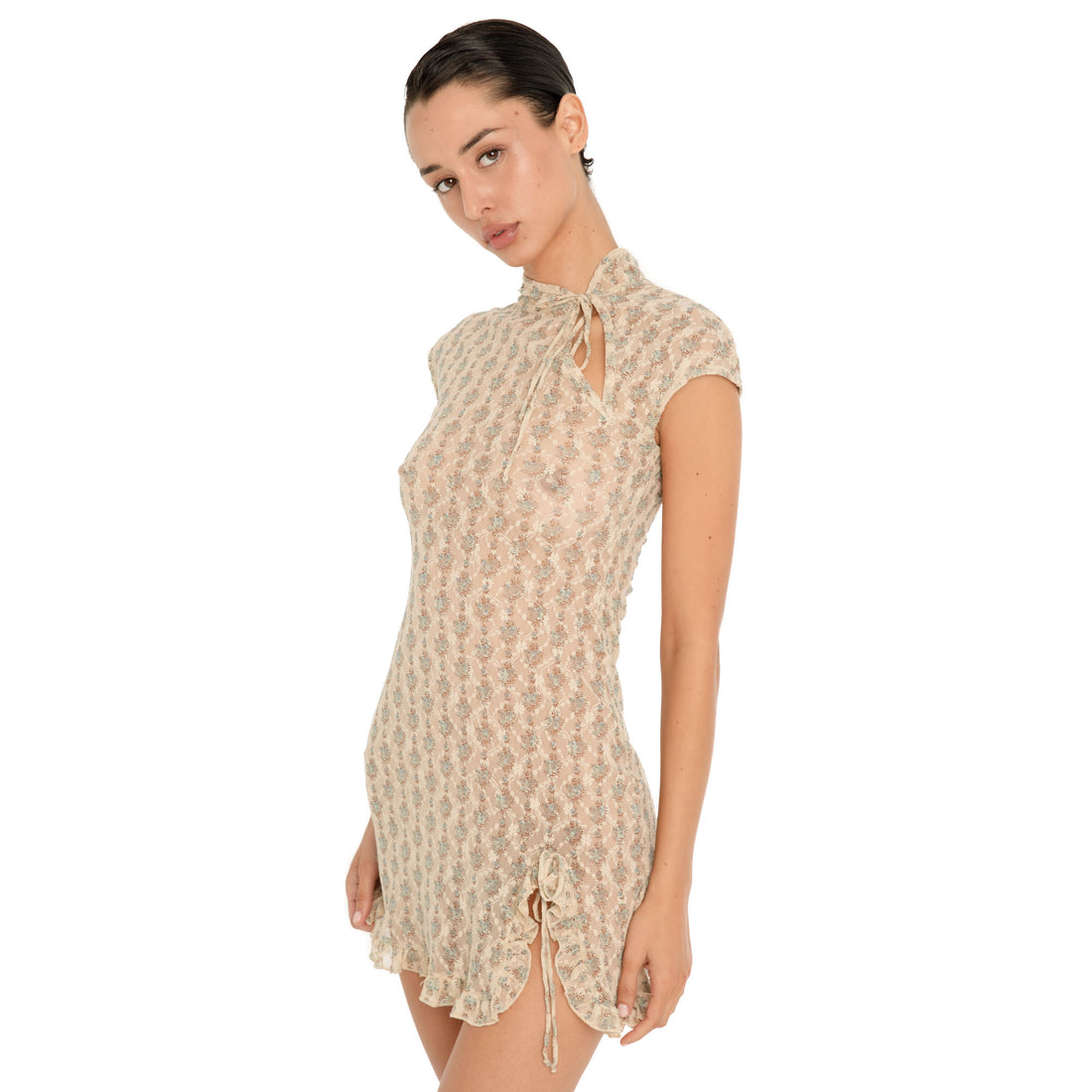 Close up three quarter view of the Bibi Dress in Sky Blossom, highlighting the delicate floral lace, cap sleeves, tie neckline with keyhole opening, fitted shape, ruffled hem, and adjustable side slit. **Sky Blossom