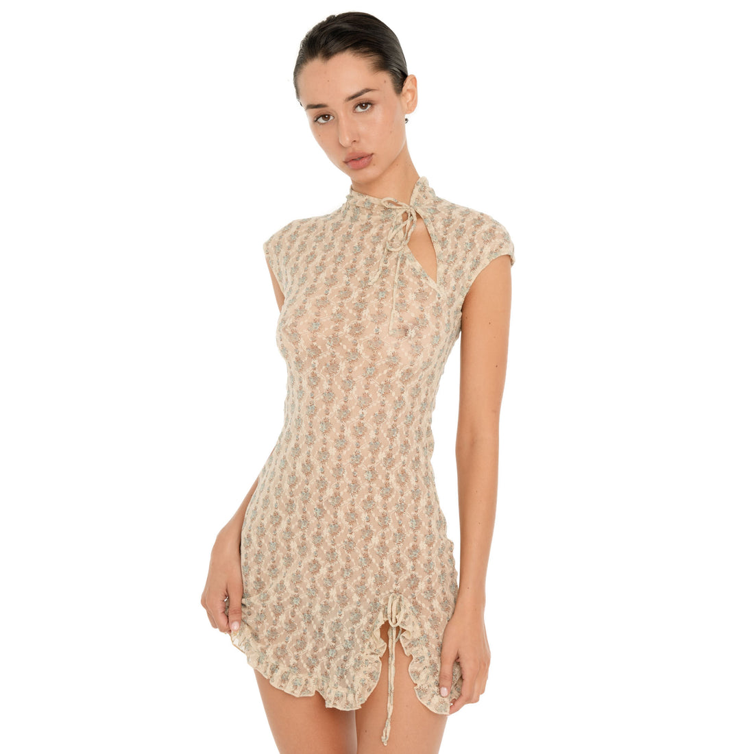 Three quarter front view of the Bibi Dress in Sky Blossom, featuring a sheer floral lace design, tie neckline with keyhole detail, fitted waist, ruffled hem, and adjustable side slit. **Sky Blossom