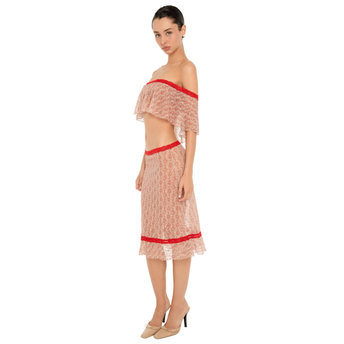 Full-length side three-quarter view of a model wearing the Cherry Blossom Liulu Skirt, showing the sheer floral lace, low-rise fit, red lace trim, and softly ruffled midi hem. **cherry blossom