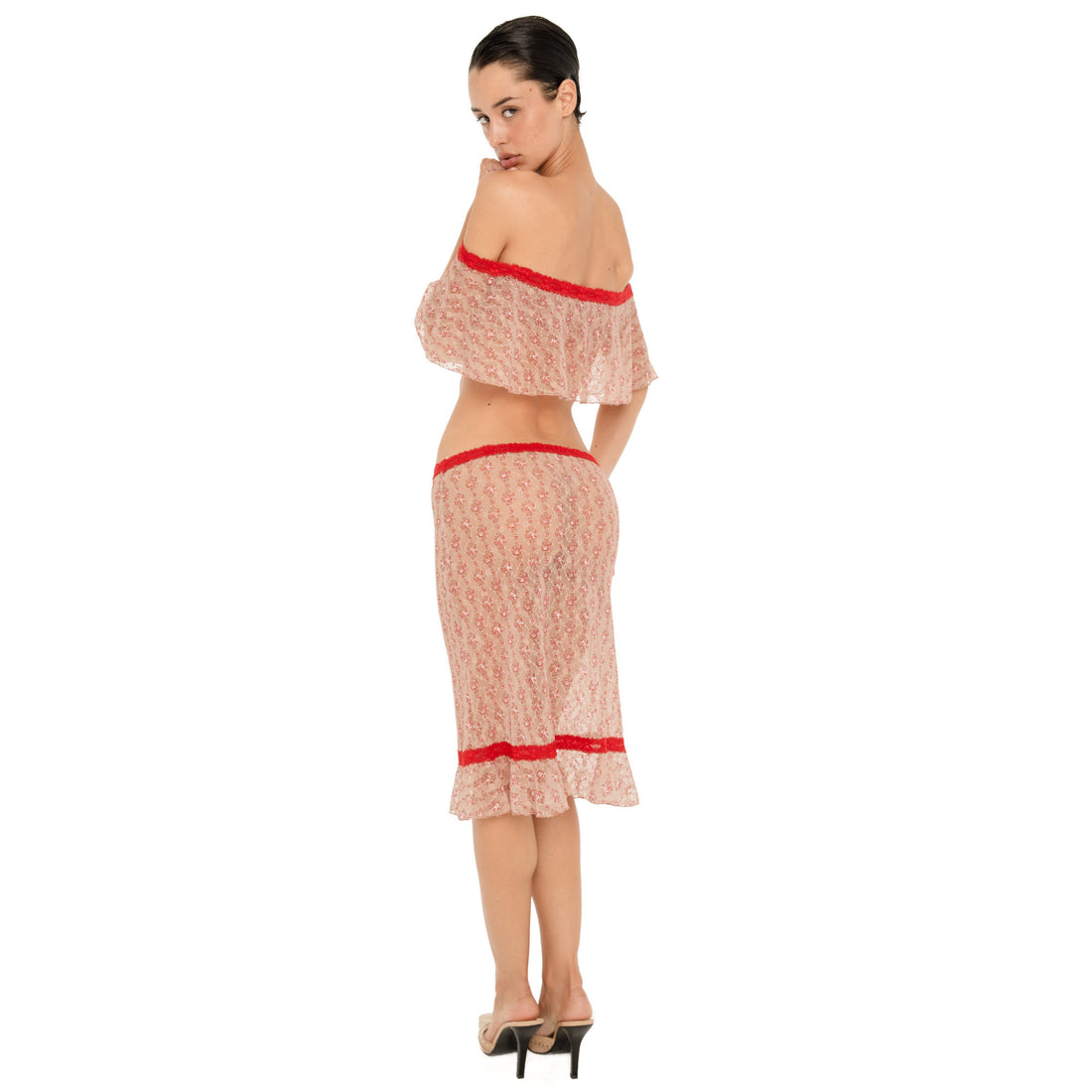 Full-length back three-quarter view of a model wearing the Cherry Blossom Liulu Skirt, showing the low-rise waistband, sheer floral lace construction, red lace trim, and ruffled midi hem from behind. **cherry blossom
