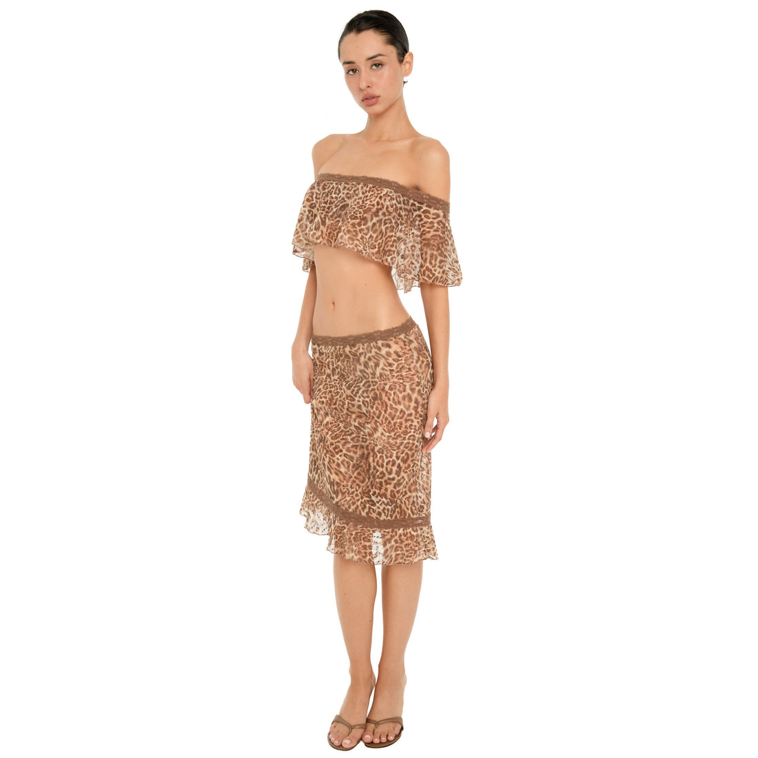 Side view of model wearing the ARE YOU AM I Liulu Skirt in leopard, showing its low rise fit, sheer fabric and ruffled hem.