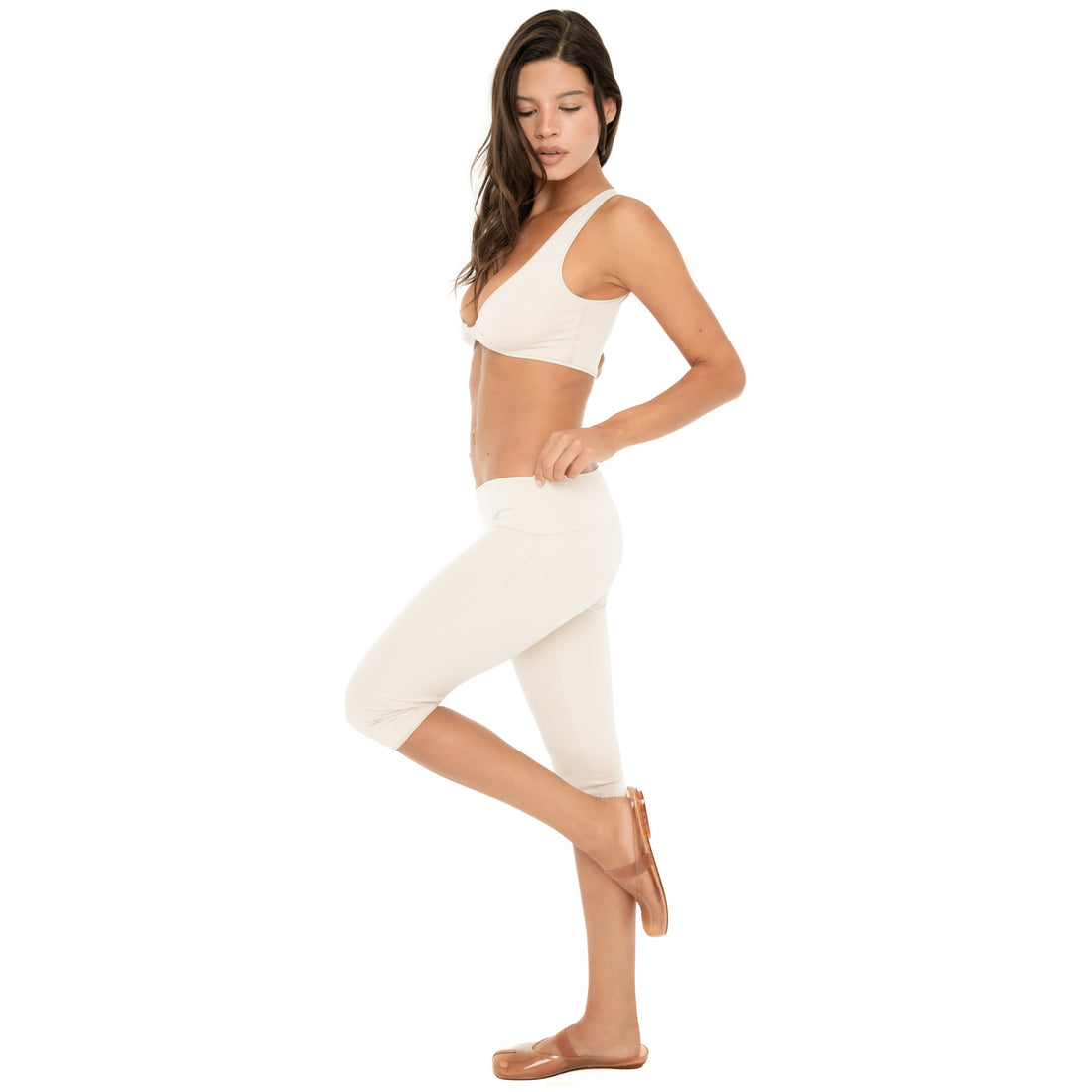 Side view: Side profile of the sand Clio Capri, showing the low-rise fold-over waistband, fitted shape through the hips and legs, and cropped capri length **sand