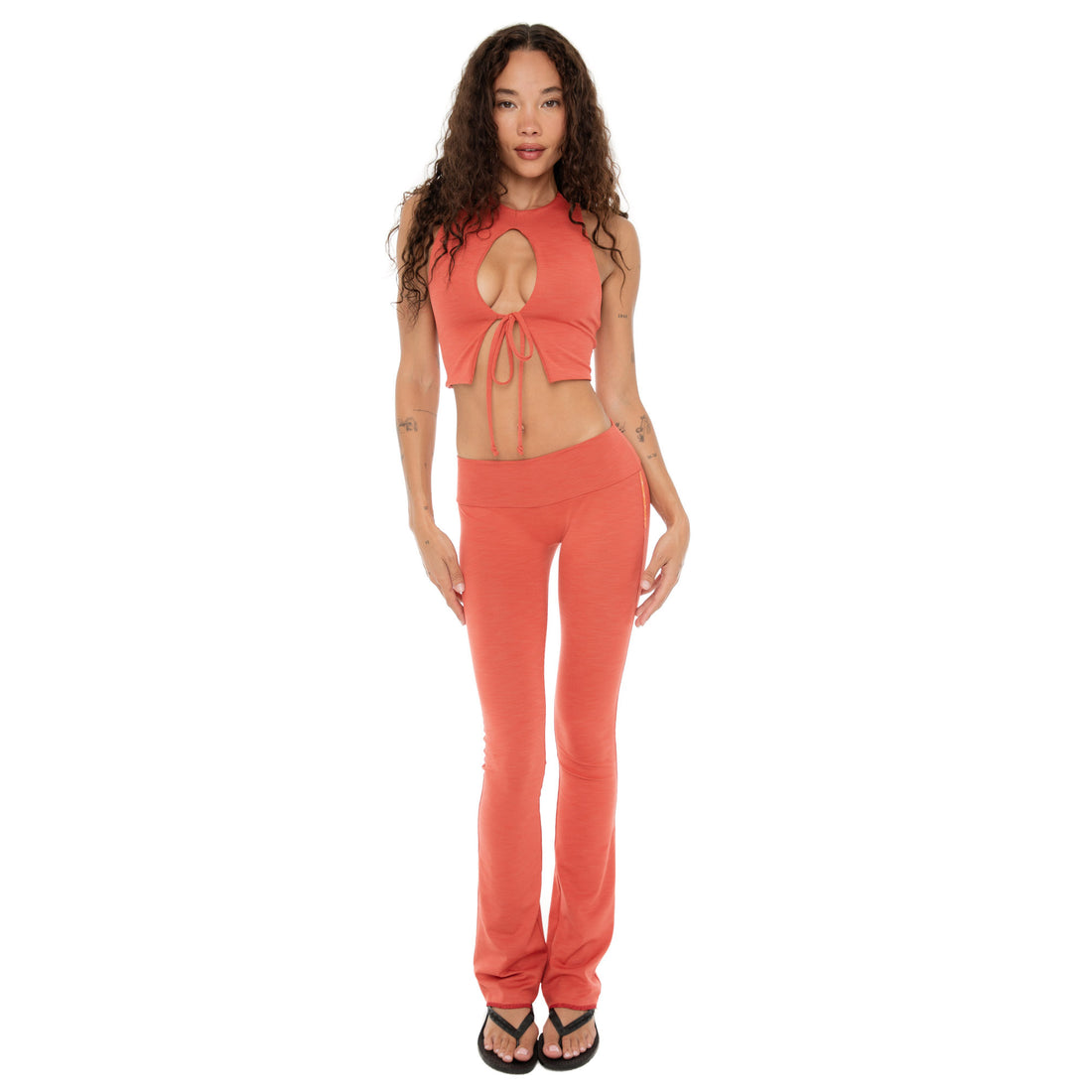Full-body front view of model wearing Are You Am I Clio Pant in Cayenne, low-rise flare in ribbed stretch fabric **cayenne