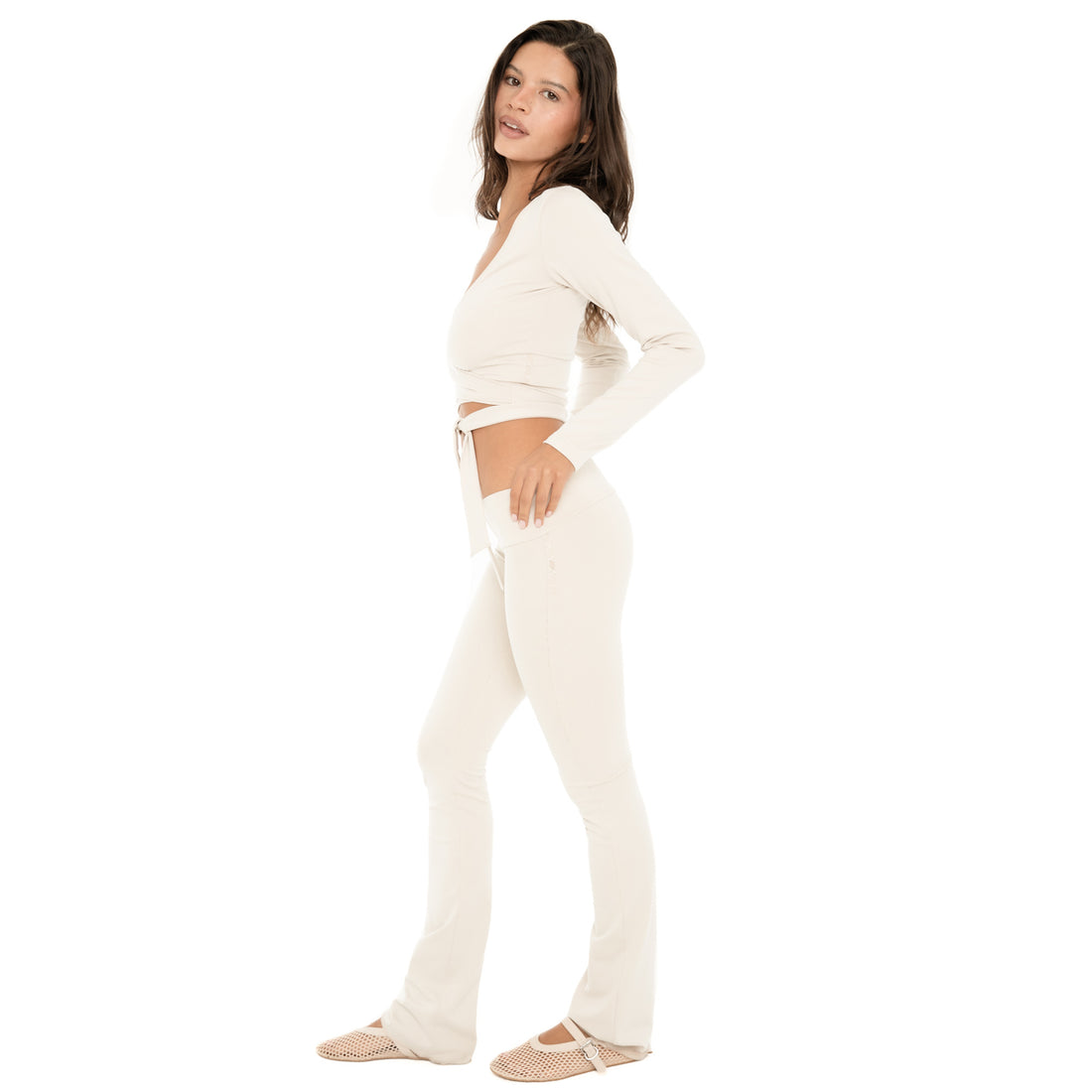 Side view: Side profile of the sand Clio Pant, showing the fitted silhouette, low-rise waistband, and slight flare through the lower leg. **sand