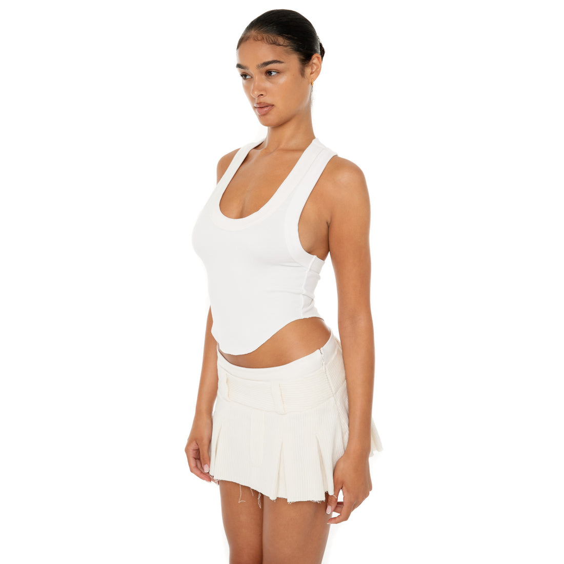 Model wearing the Cahya Skirt — a low-rise mini in wide wale corduroy with tonal embroidery and raw-edge hem, made from 100% cotton for bold structure.**ivory