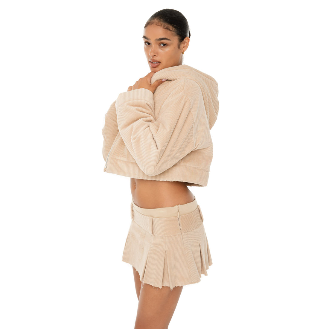 Model wearing the Cahya Skirt — a low-rise mini in wide wale corduroy with tonal embroidery and raw-edge hem, made from 100% cotton for bold structure.**sand