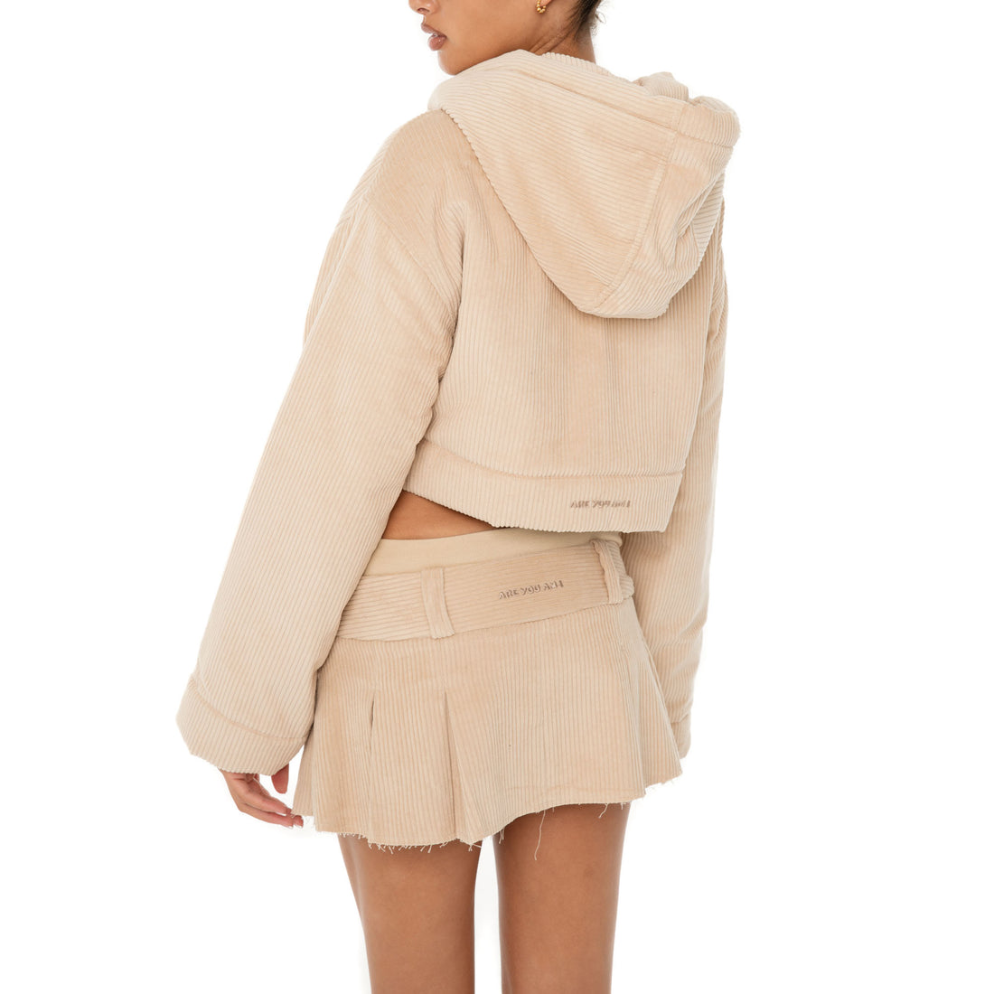 Model wearing the Cahya Skirt — a low-rise mini in wide wale corduroy with tonal embroidery and raw-edge hem, made from 100% cotton for bold structure.**sand