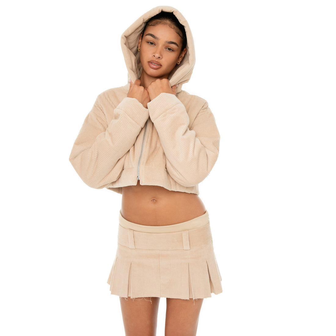 Model wearing the Cahya Skirt — a low-rise mini in wide wale corduroy with tonal embroidery and raw-edge hem, made from 100% cotton for bold structure.**sand