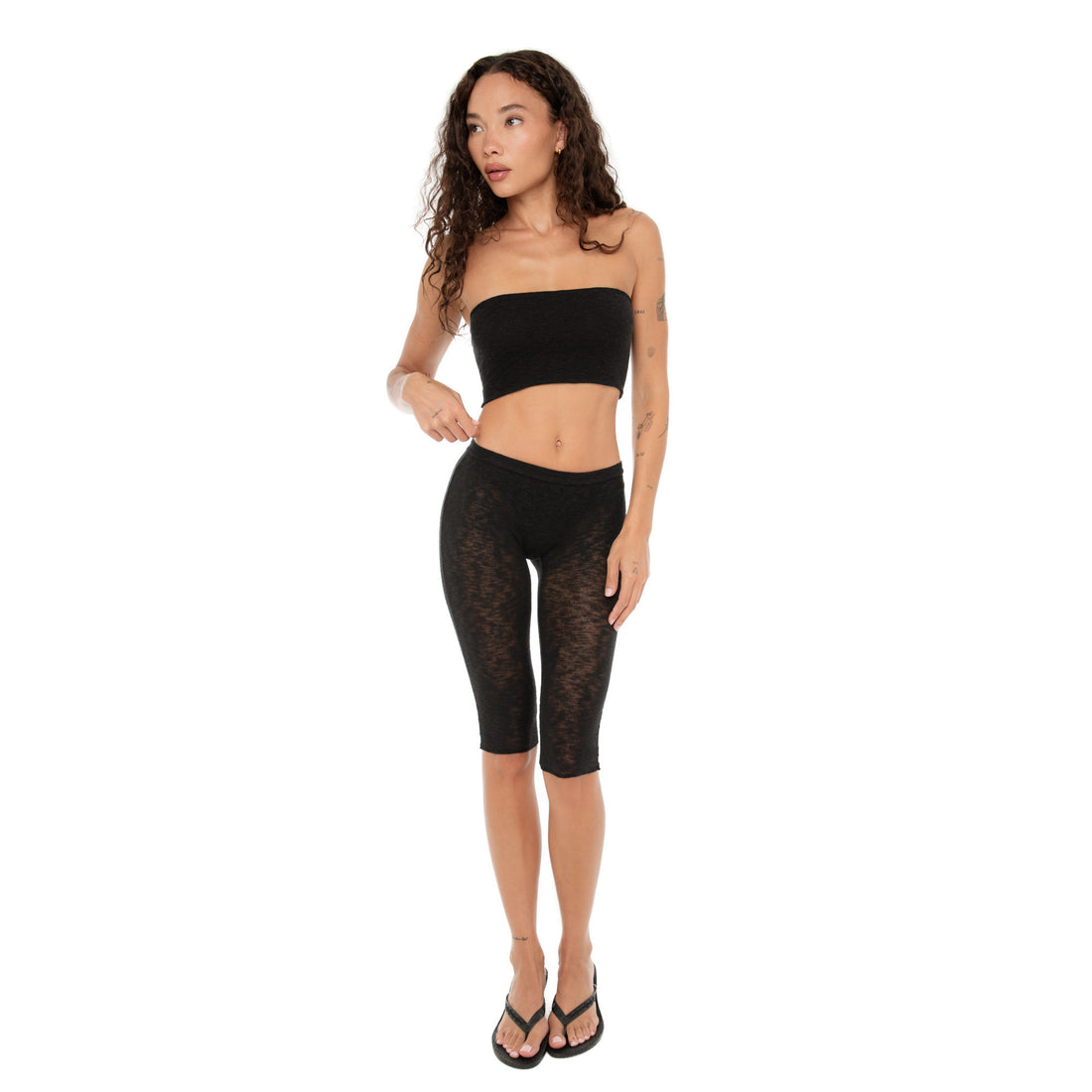 Side view of the model in the Aili Tube bandeau and black capri pants looking off to the side **black
