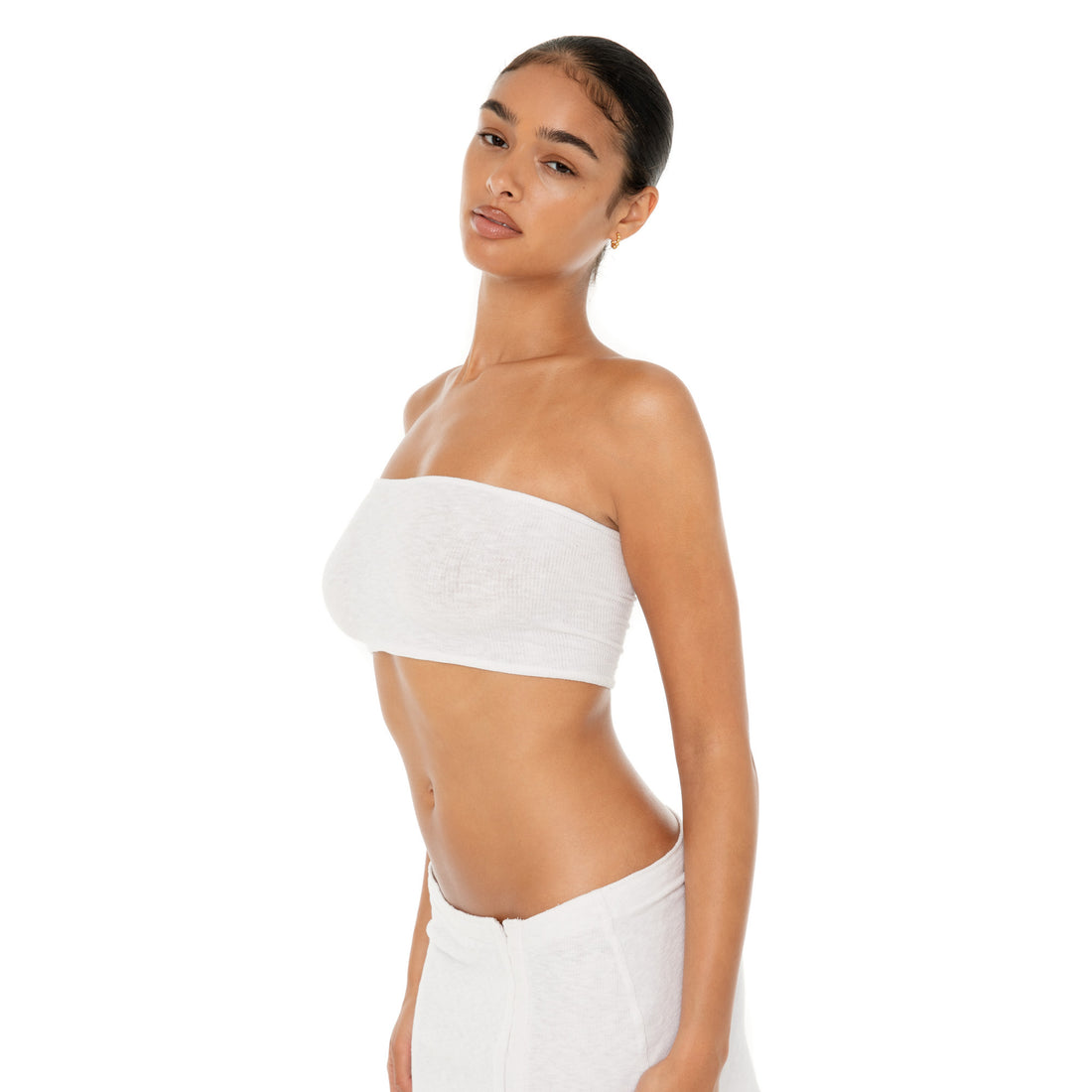 Three quarter view of the white Aili Tube showing its fitted strapless silhouette and sheer ribbed texture **white