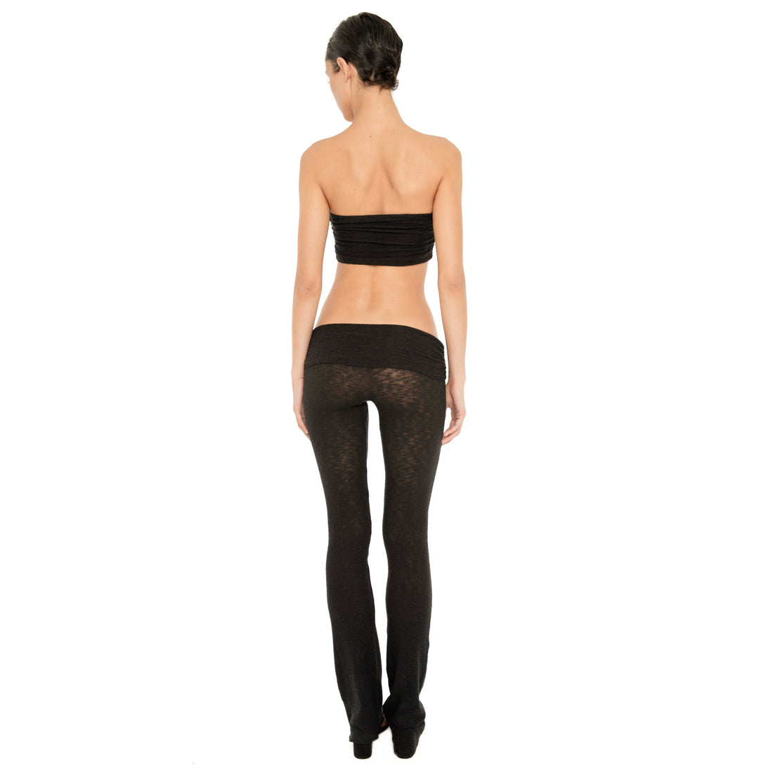 Back view of model wearing the Meili Pant in Black, showing the wide fold-over waistband, sheer fitted silhouette and full-length leg. **black