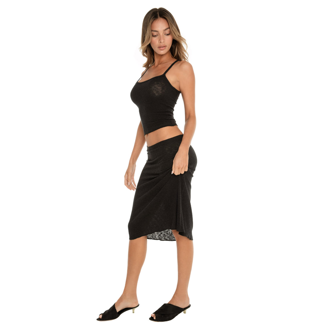 black ribbed midi skirt styled with matching top, side view showing movement and fluid hemline **black