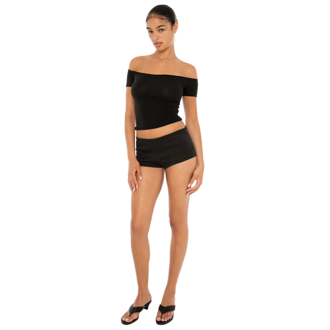 Model wearing the Ilze Top in white, an off-the-shoulder fitted jersey top made of lightweight cotton-spandex blend with raw hems **black