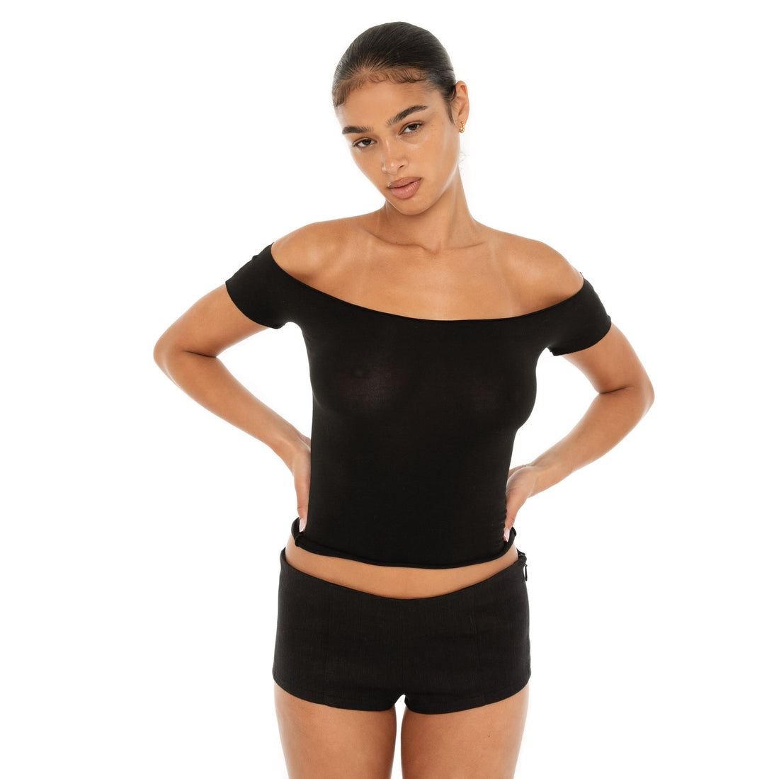 Model wearing the Ilze Top in white, an off-the-shoulder fitted jersey top made of lightweight cotton-spandex blend with raw hems **black