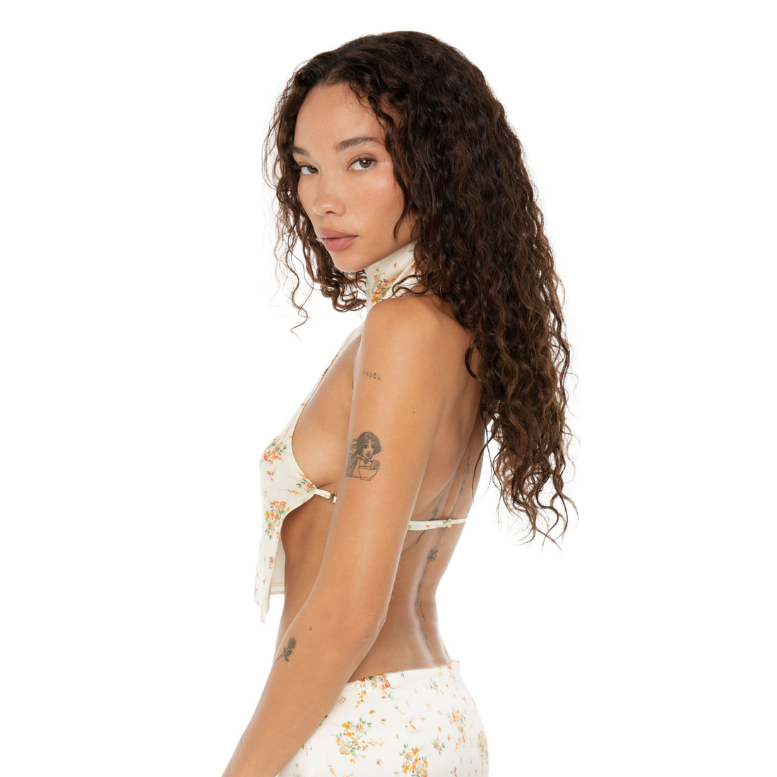 Side profile of model highlighting the Kiku Top’s open side and halter neck design with delicate floral print. **ivory