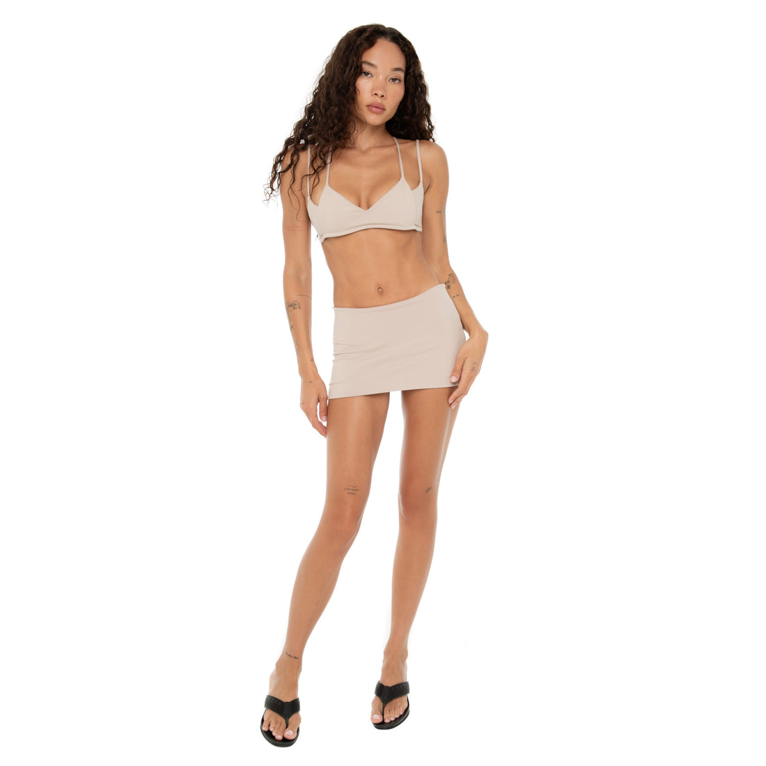 Full-length view of model wearing Iida Bra in nude styled with matching mini skirt. **nude