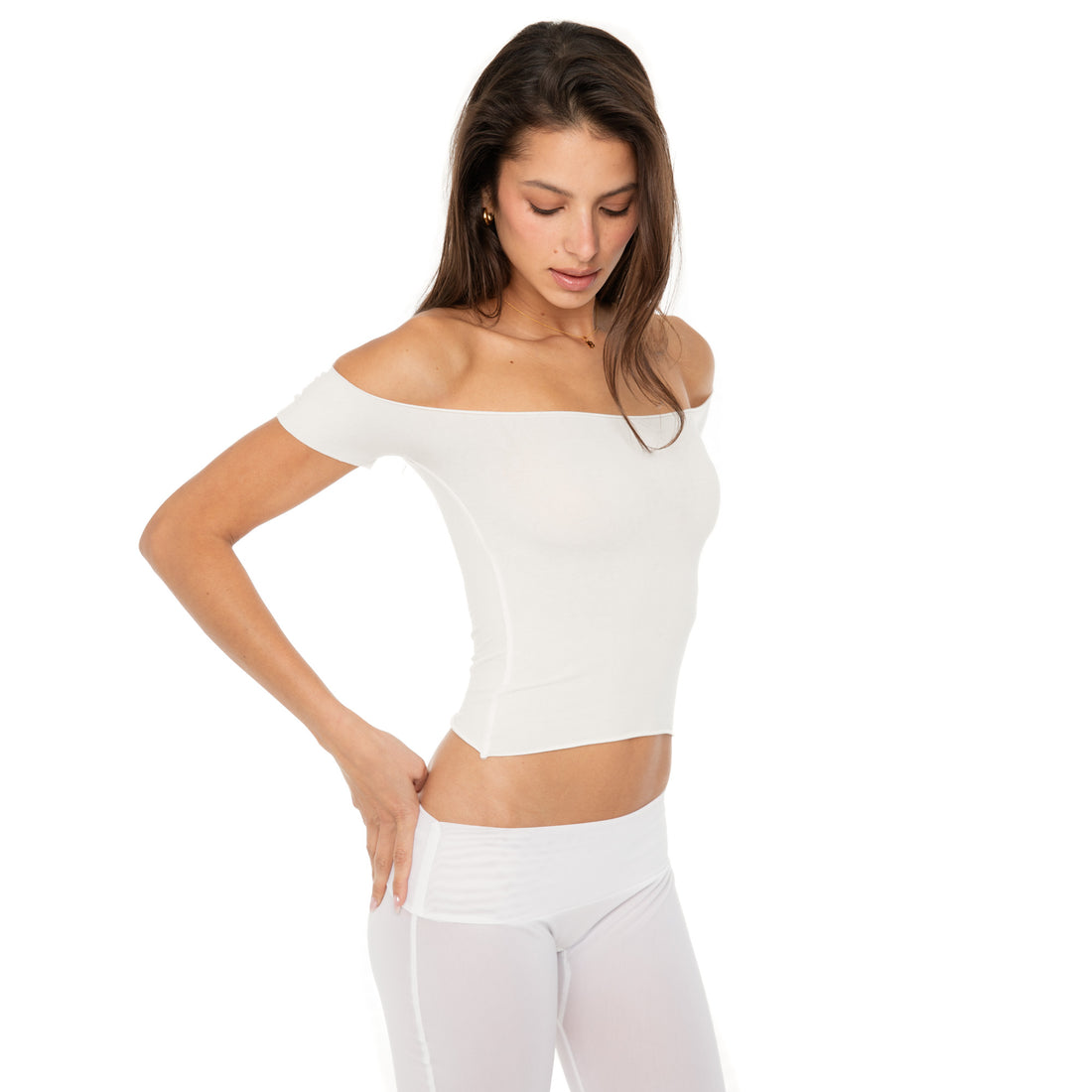 Model wearing the Ilze Top in white, an off-the-shoulder fitted jersey top made of lightweight cotton-spandex blend with raw hems **white