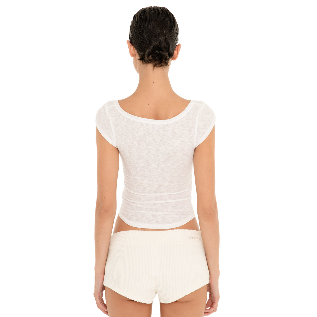 Back view of model wearing the ivory Nimue Short, showing the low-rise fit, short hemline and tonal ARE YOU AM I embroidery at the waistband. **ivory