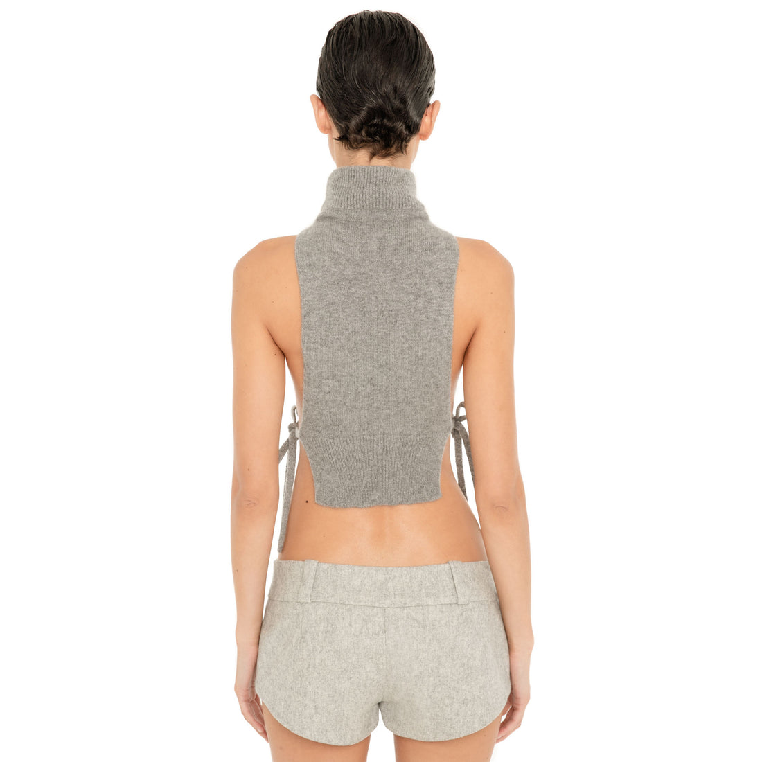 Back view of model wearing the Nula Short in Dove, showing the low rise waistband, belt loops and curved micro hem. **dove