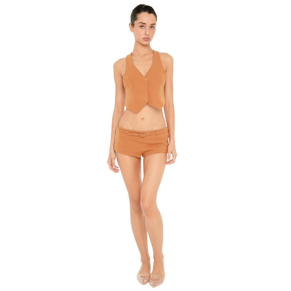 Full-length front view of model wearing the ARE YOU AM I Pika Short in Saffron, a low-rise micro short with a matching skinny belt, styled with a coordinating vest. **saffron