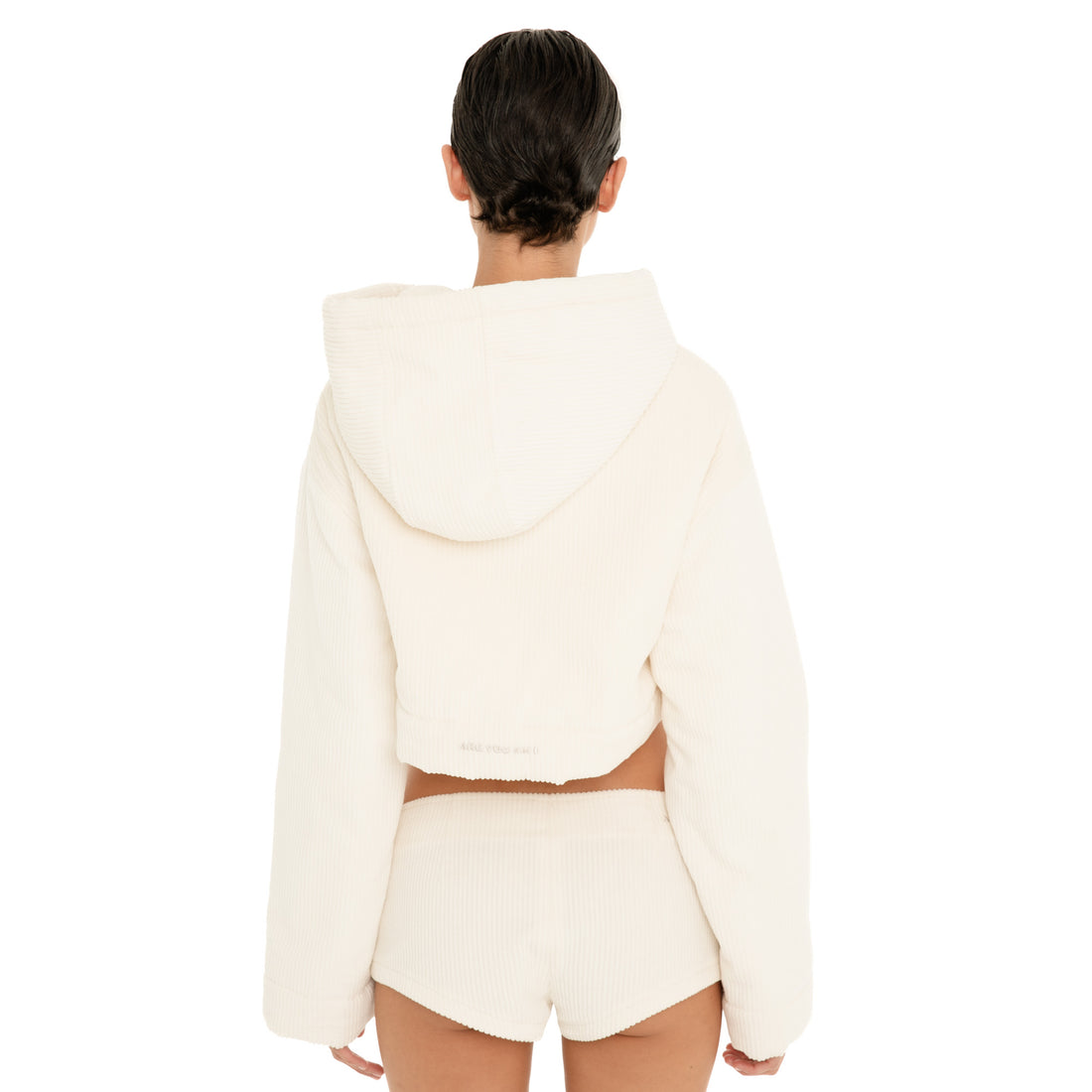 Back view of model wearing the ivory Sfera Jacket, showing the oversized hood, cropped hem and subtle ARE YOU AM I embroidery at the back. **ivory