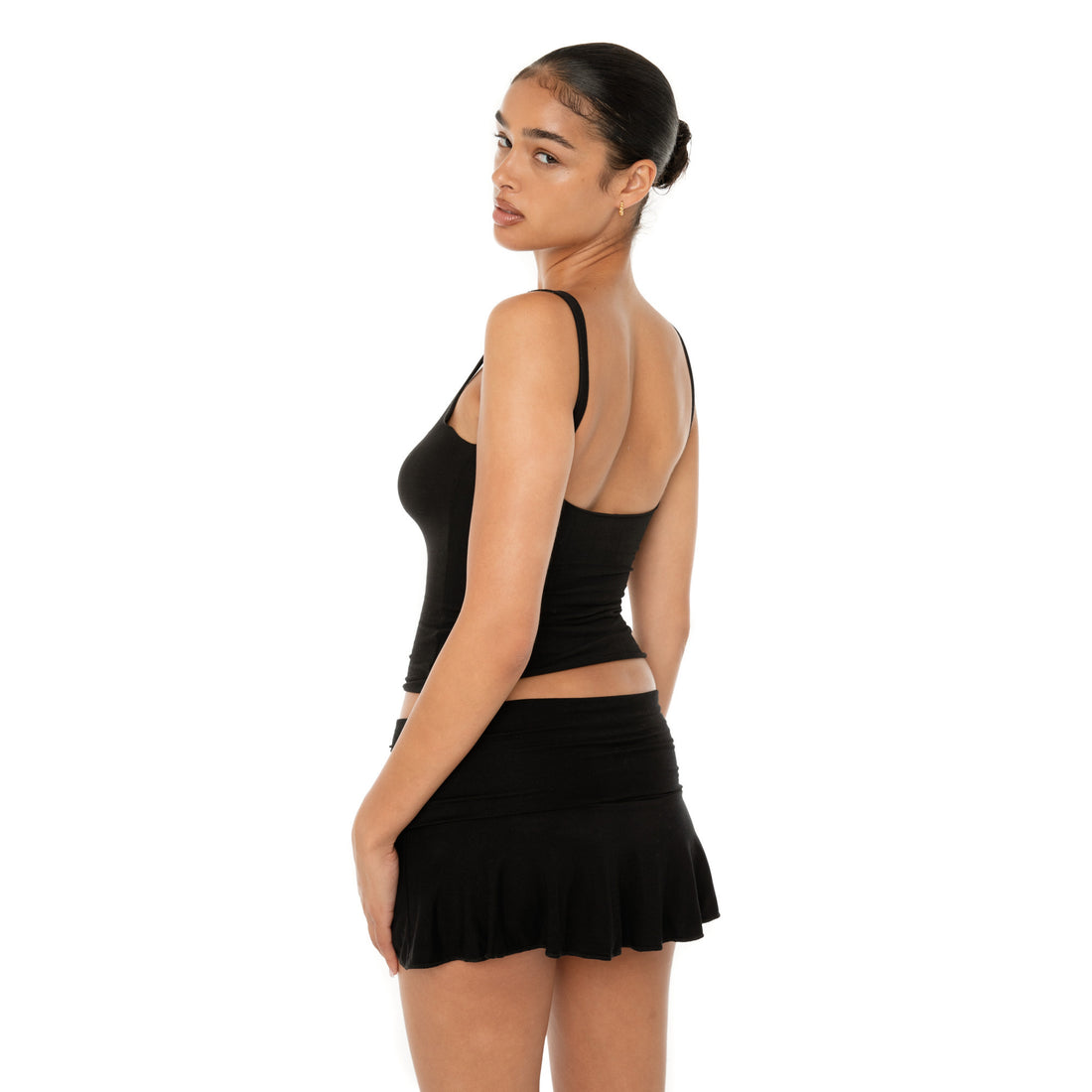 Model wearing the Naia Skirt — a low-rise mini in ultra-soft modal with spandex stretch, designed to sculpt the waist with a sleek, minimal fit.**black