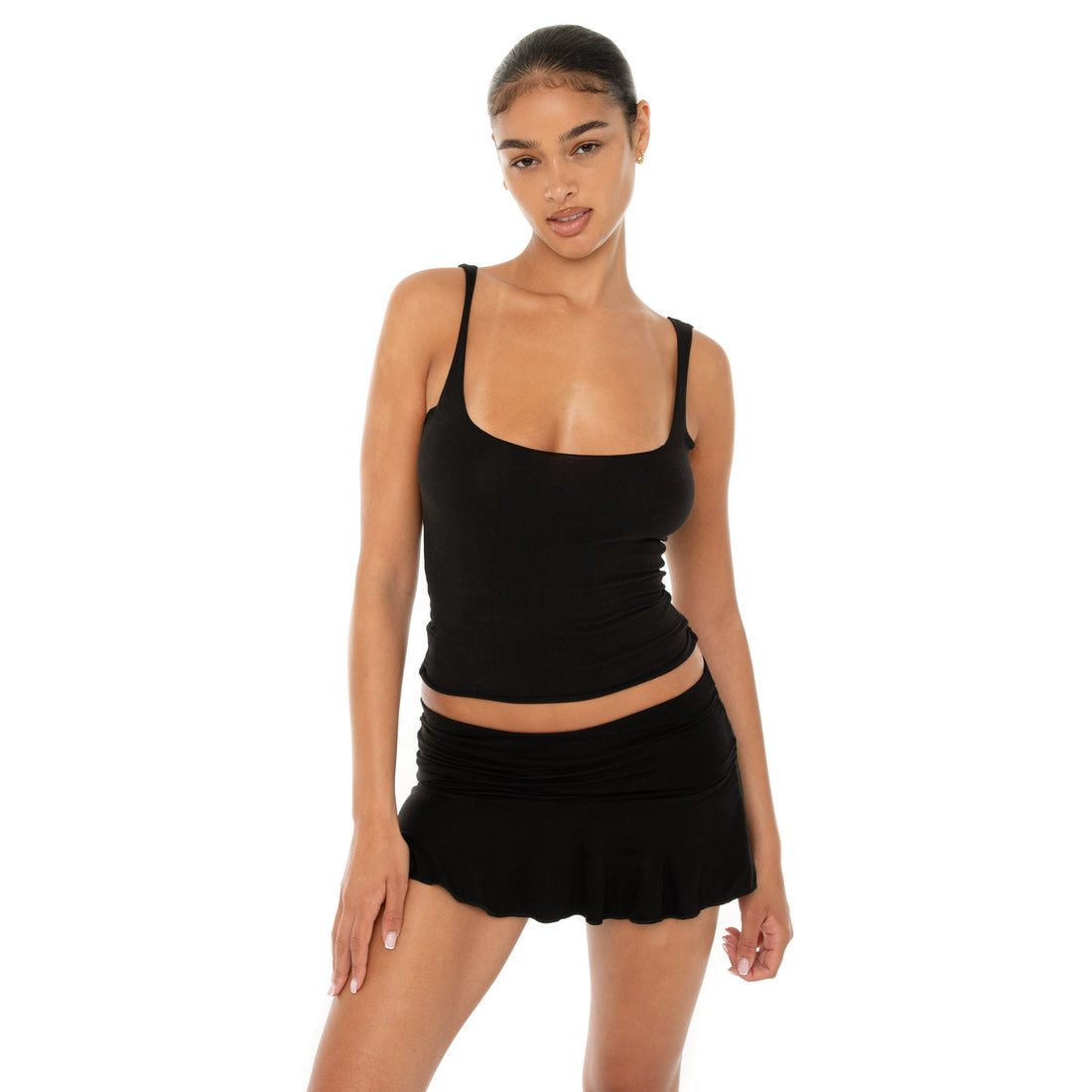 Model wearing the Naia Skirt — a low-rise mini in ultra-soft modal with spandex stretch, designed to sculpt the waist with a sleek, minimal fit.**black
