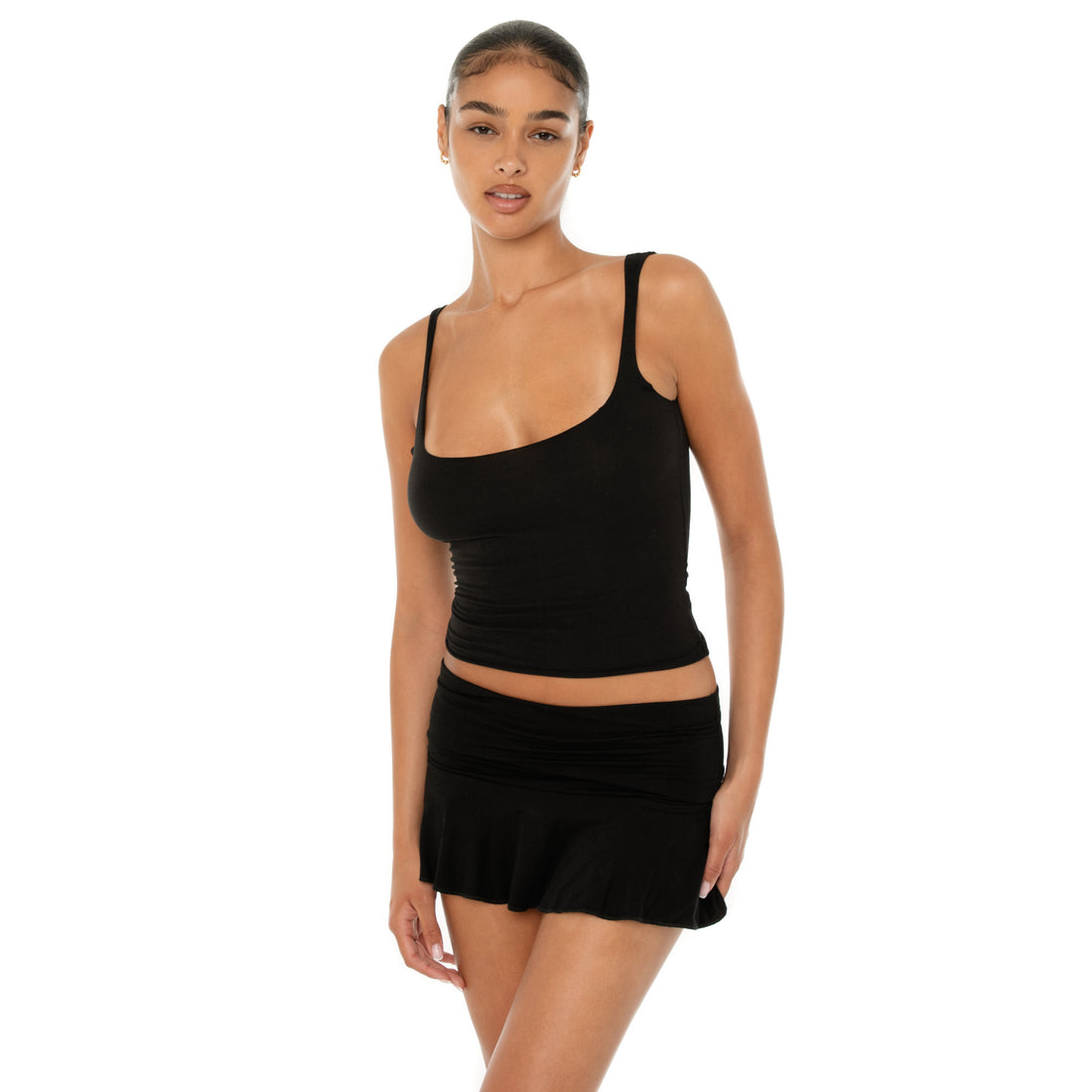 Model wearing the Naia Skirt — a low-rise mini in ultra-soft modal with spandex stretch, designed to sculpt the waist with a sleek, minimal fit.**black