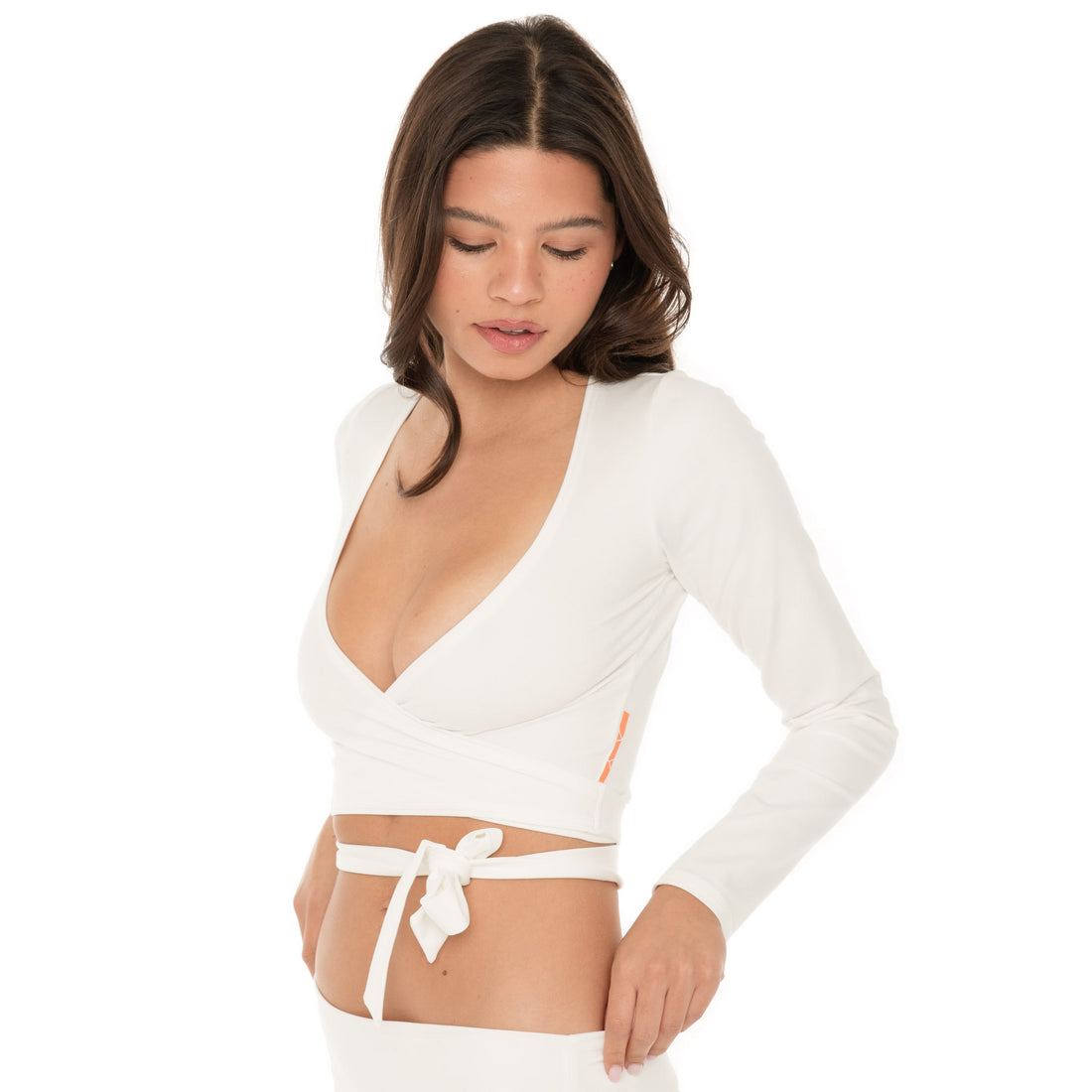 Close-up of model in a white long-sleeve wrap top with deep V neckline and tie waist, shown from the front. **white