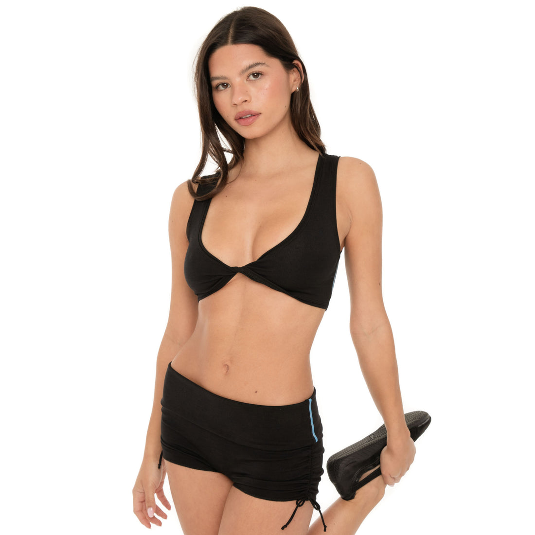 Model stretching in black ribbed low-rise active shorts with ruched adjustable sides **black