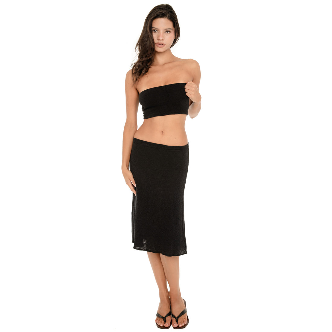Full length front view of the Aili Tube in black, styled with a low rise black midi skirt **black
