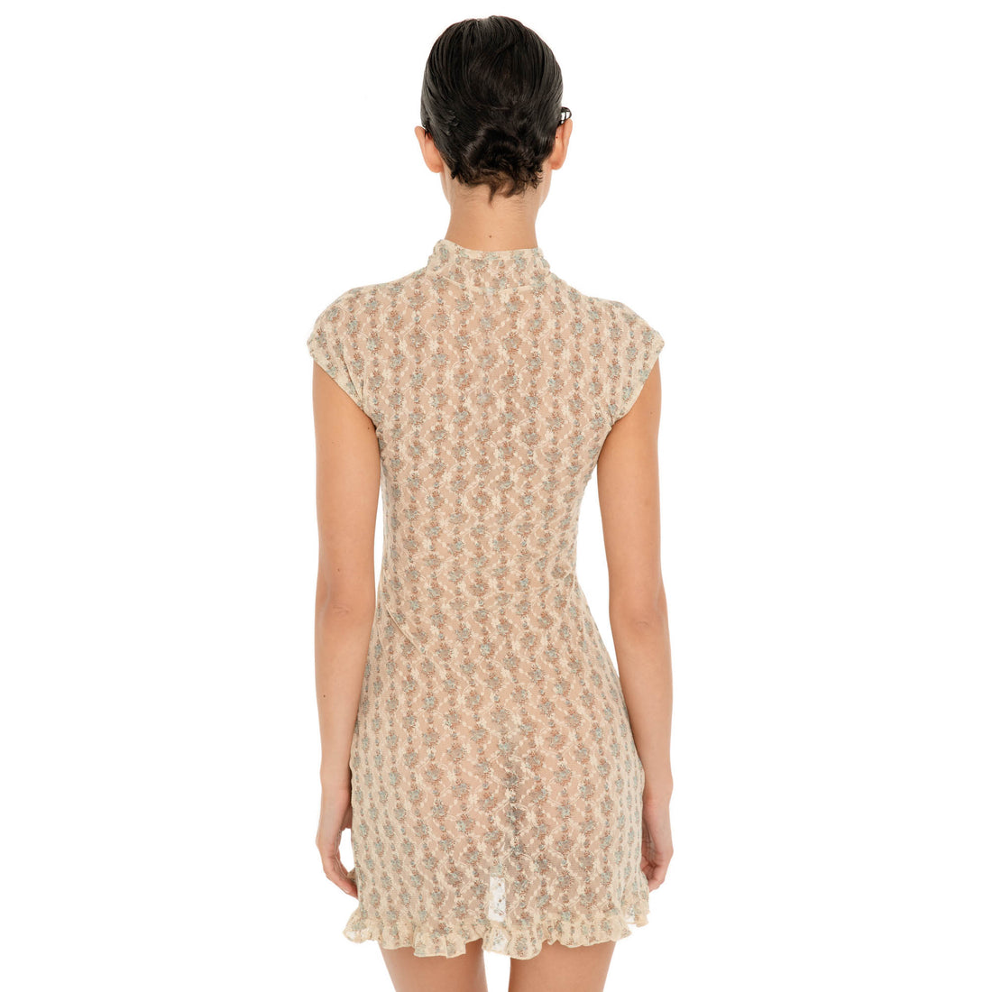 Three quarter front view of the Bibi Dress in Sky Blossom, featuring a sheer floral lace design, tie neckline with keyhole detail, fitted waist, ruffled hem, and adjustable side slit. **Sky Blossom