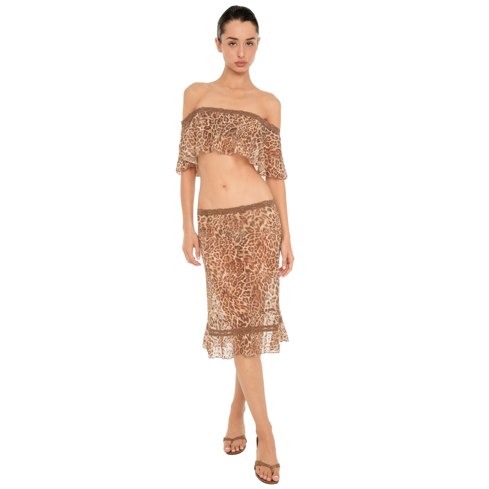 Side view of model wearing the ARE YOU AM I Liulu Skirt in leopard, showing its low rise fit, sheer fabric and ruffled hem.