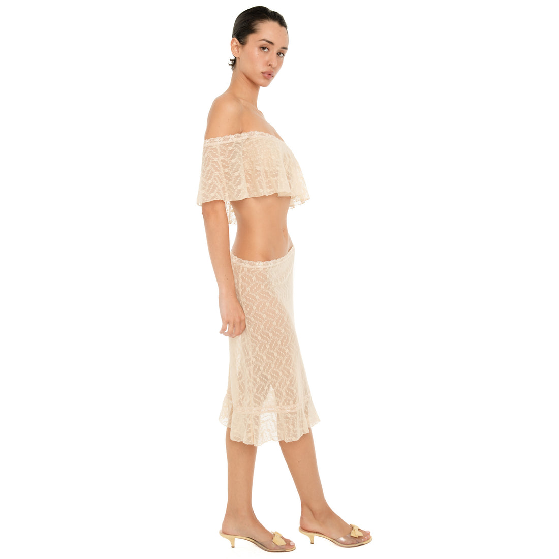 Side view of the Liulu skirt in nude, showing its sheer floral lace construction, fitted silhouette, low rise waist, and ruffled hem. **nude
