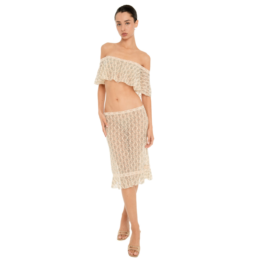 Model wearing the Liulu skirt, a sheer cream floral lace midi skirt with a low-rise waist, lace trim, and ruffled hem, styled with a matching off-the-shoulder top. **sky blossom