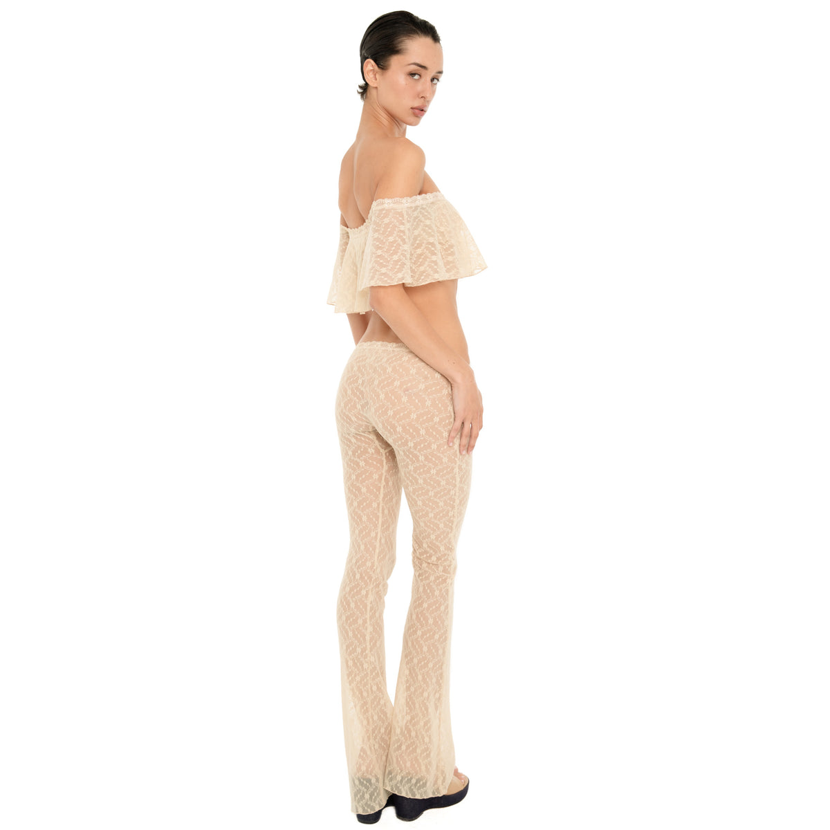 Back three-quarter view of the Liani Pant in Nude, showing the sheer floral lace, low rise fit and fitted-to-flared silhouette. **nude