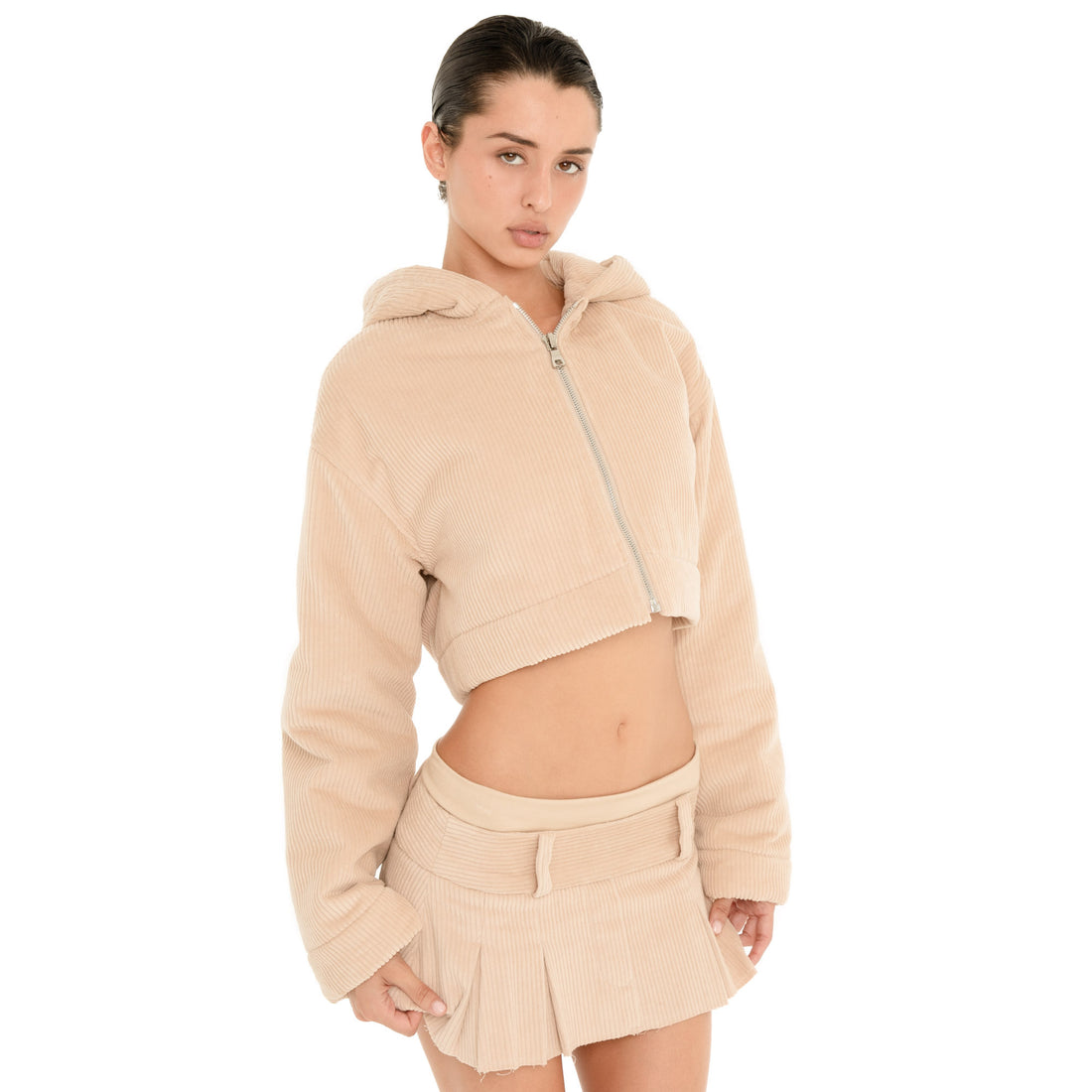 Front view of model wearing the Cahya Skirt in Sand, showing the corduroy texture, low rise waistband, belt loops and pleated hem. **sand