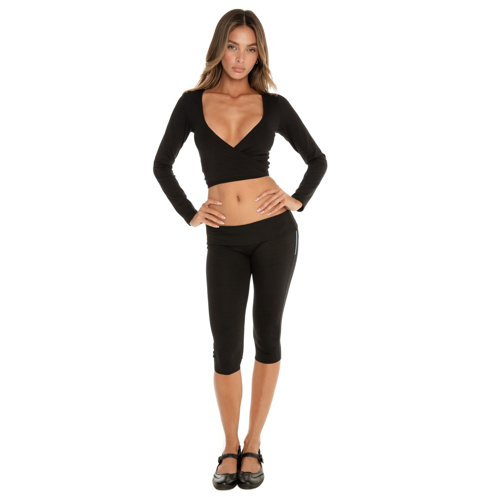 Model standing front-facing in the Clio Capri in black, mid-calf length with low-rise fit and smooth waistband, styled with the Nuka Top, hands on hips **black