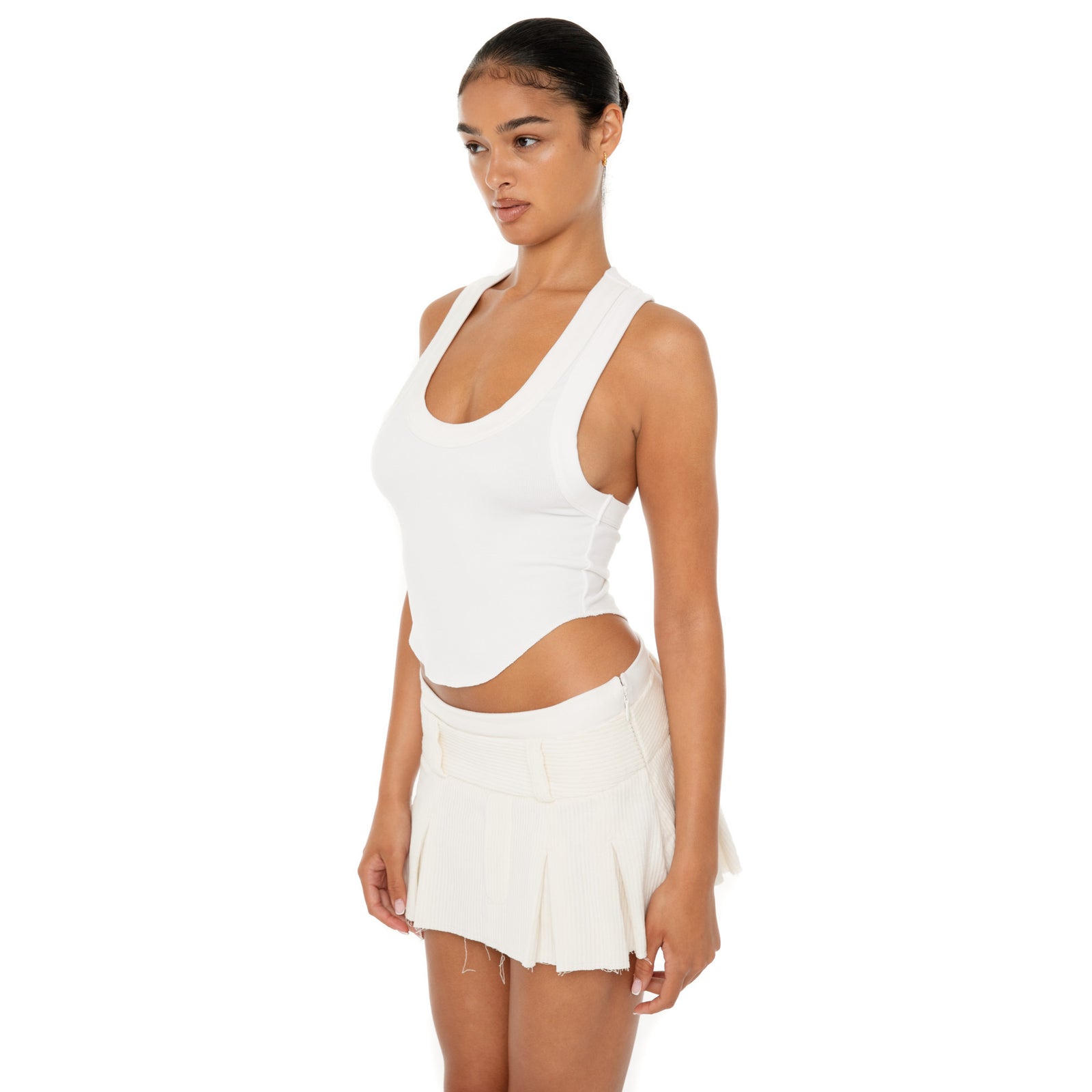 Model wearing the Cahya Skirt — a low-rise mini in wide wale corduroy with tonal embroidery and raw-edge hem, made from 100% cotton for bold structure.**ivory