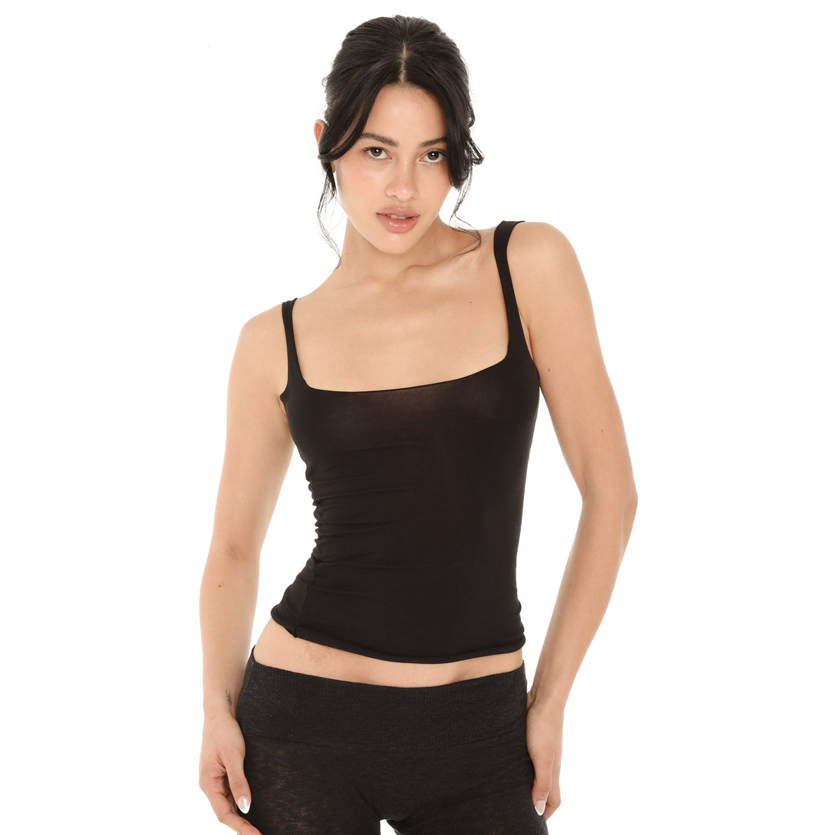 Model in the black Elix Tank, showing the wide square neckline, the sheer fine-knit fabric and the raw rolled hem at the waist **black