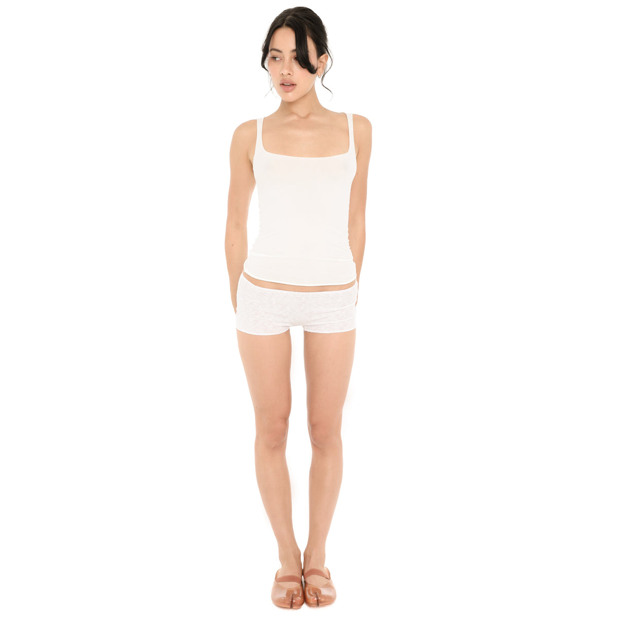 Model wearing the Elix Tank in white, a fitted sheer knit tank with a square neckline and wide straps, styled with white knit shorts and pink ballet flats **white