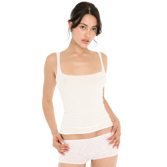 Model in the white Elix Tank, showing the square neckline, the fitted length to the hip and the rolled hem, worn with white knit shorts **white