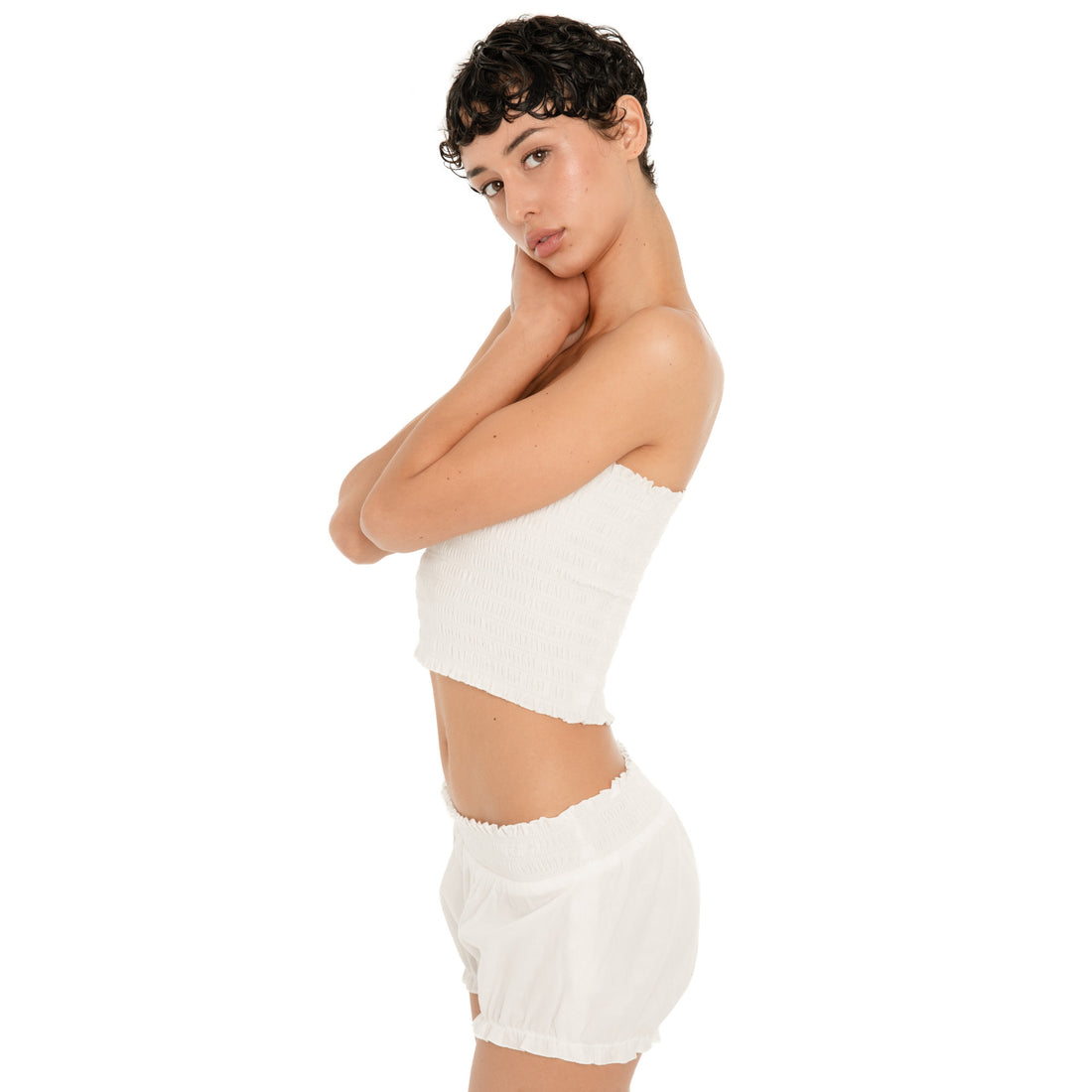 Side view of the Eran Bloomer in white, showing the low rise smocked waistband, relaxed fit, and gathered ruffled leg openings.