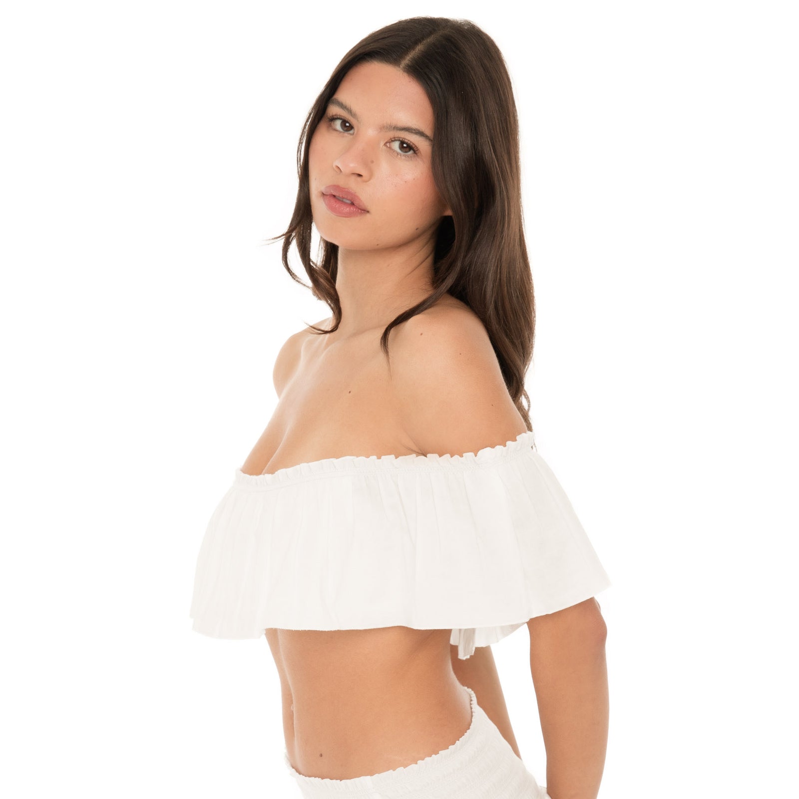 Close side view of the white ruffle bandeau worn off the shoulders. The layered ruffle drapes over the upper arms with a softly gathered top edge.