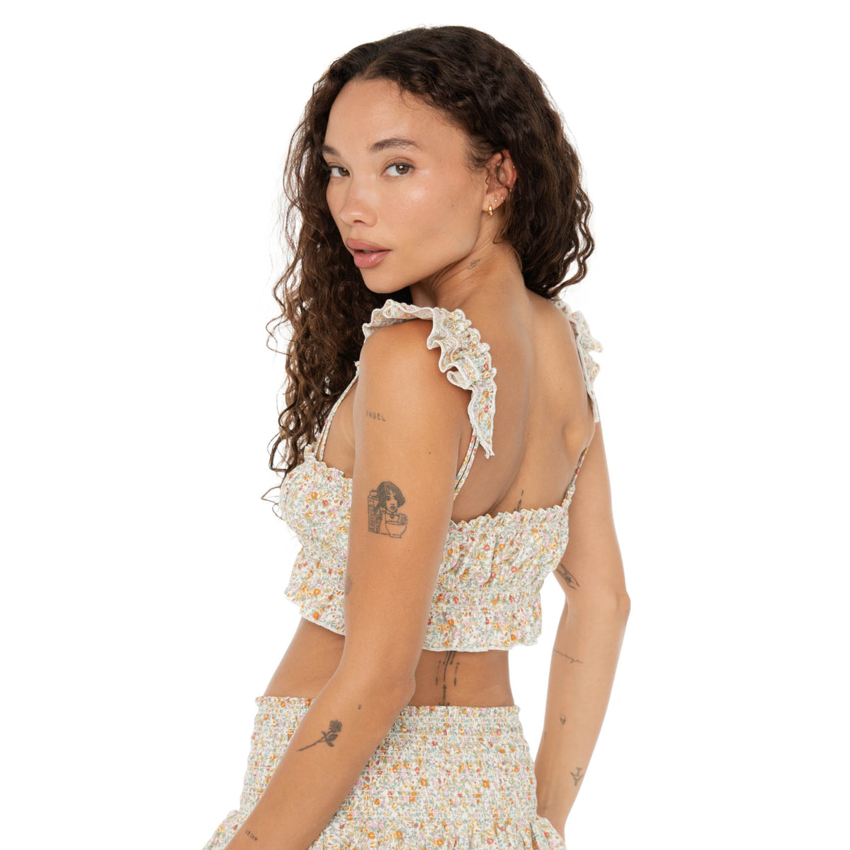 Side view of model in the Are You Am I Eran Top floral smocked crop top, featuring ruffle straps and a fitted silhouette, styled with the Eran Skirt. **floral