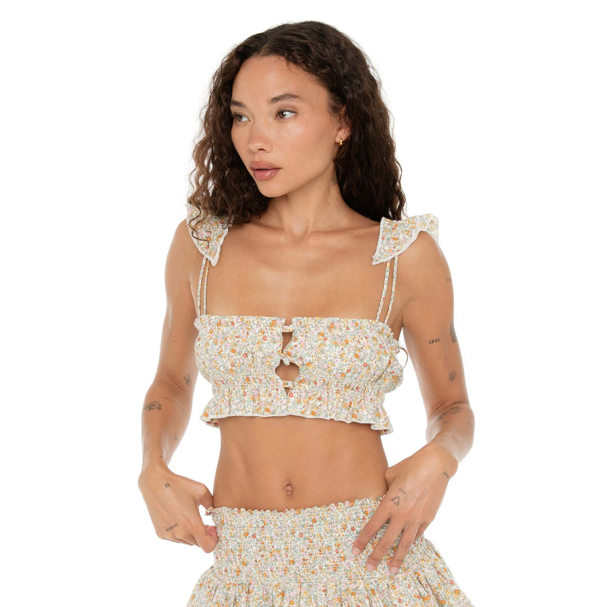 Model in the Are You Am I Eran Top floral print, featuring smocked fabric, ruffle details, and front button closures, paired with the Eran Skirt. **floral