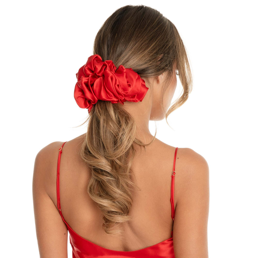 Back view of a model wearing an oversized silk scrunchie securing a low ponytail, highlighting the voluminous gathered shape and glossy charmeuse finish **cherry-red