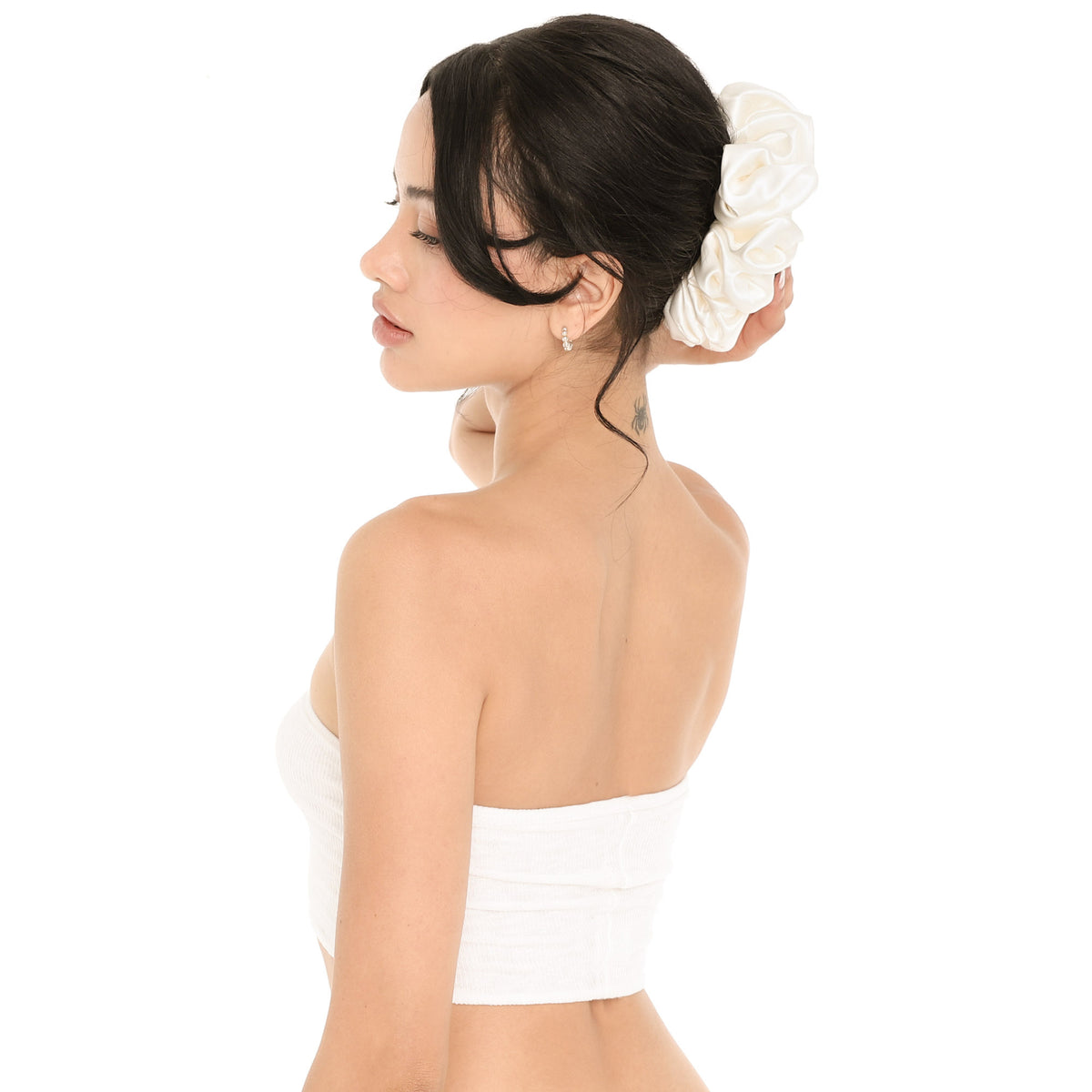 Model wearing the white silk Faeli Scrunchie around a low bun, showing the oversized ruffled shape against dark hair, worn with the white Aili Tube **white